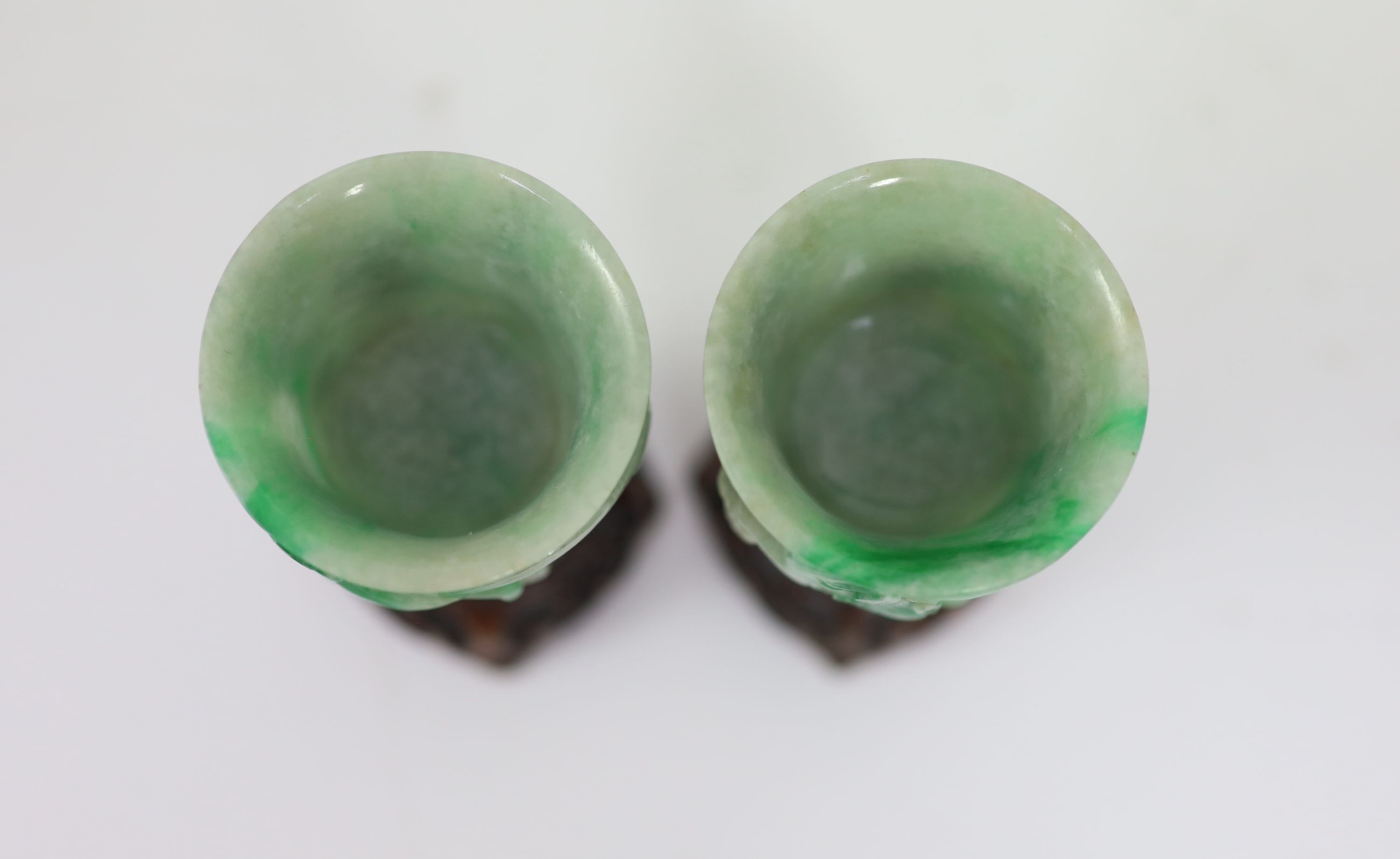 A pair of Chinese small jadeite stem cups, 20th century, 7.2cm high, carved wood stands
